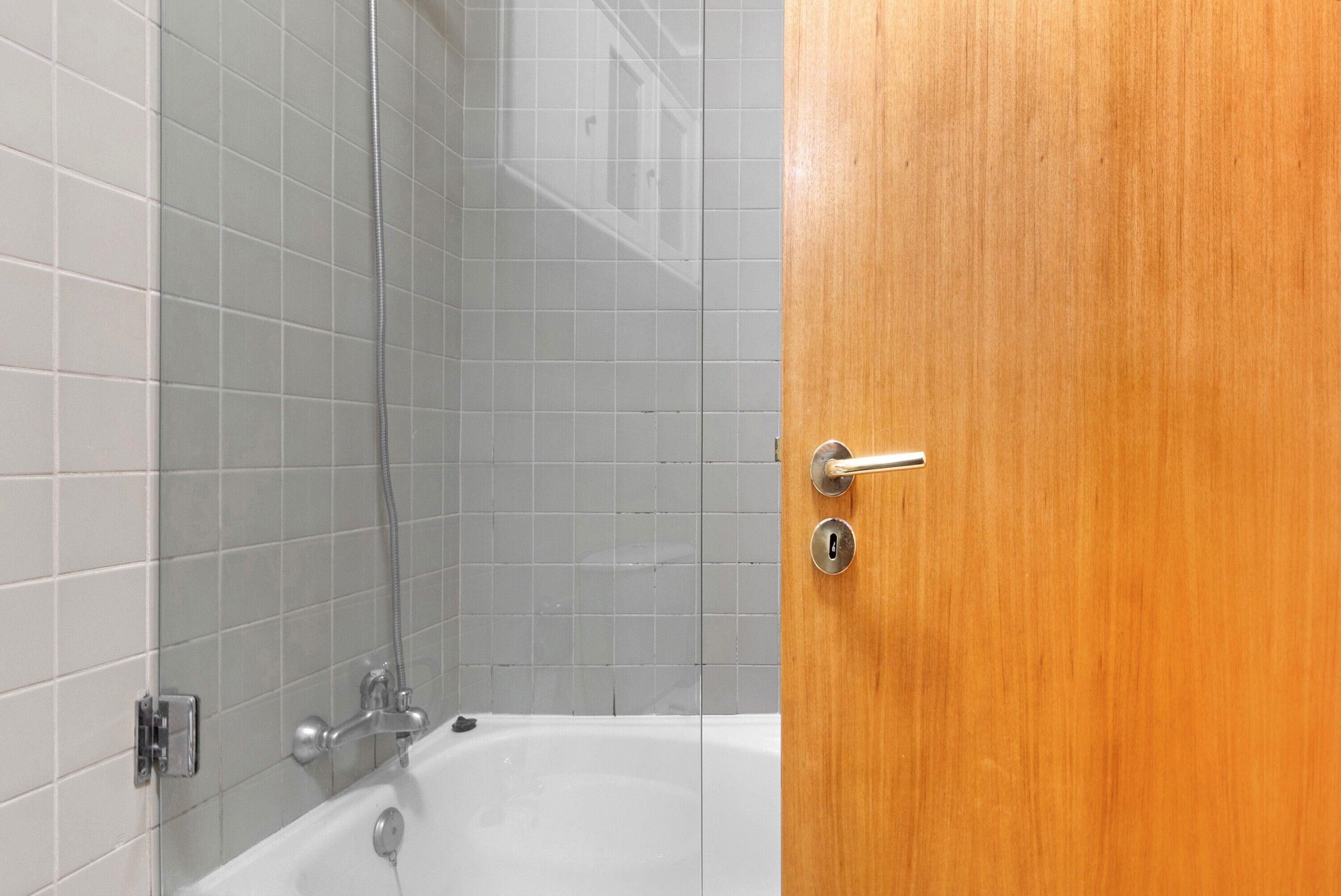 A bathroom with a bathtub, a shower, and a wooden door.