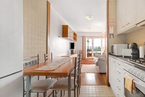 A kitchen with a dining table, chairs, a refrigerator, a microwave, and a stove.