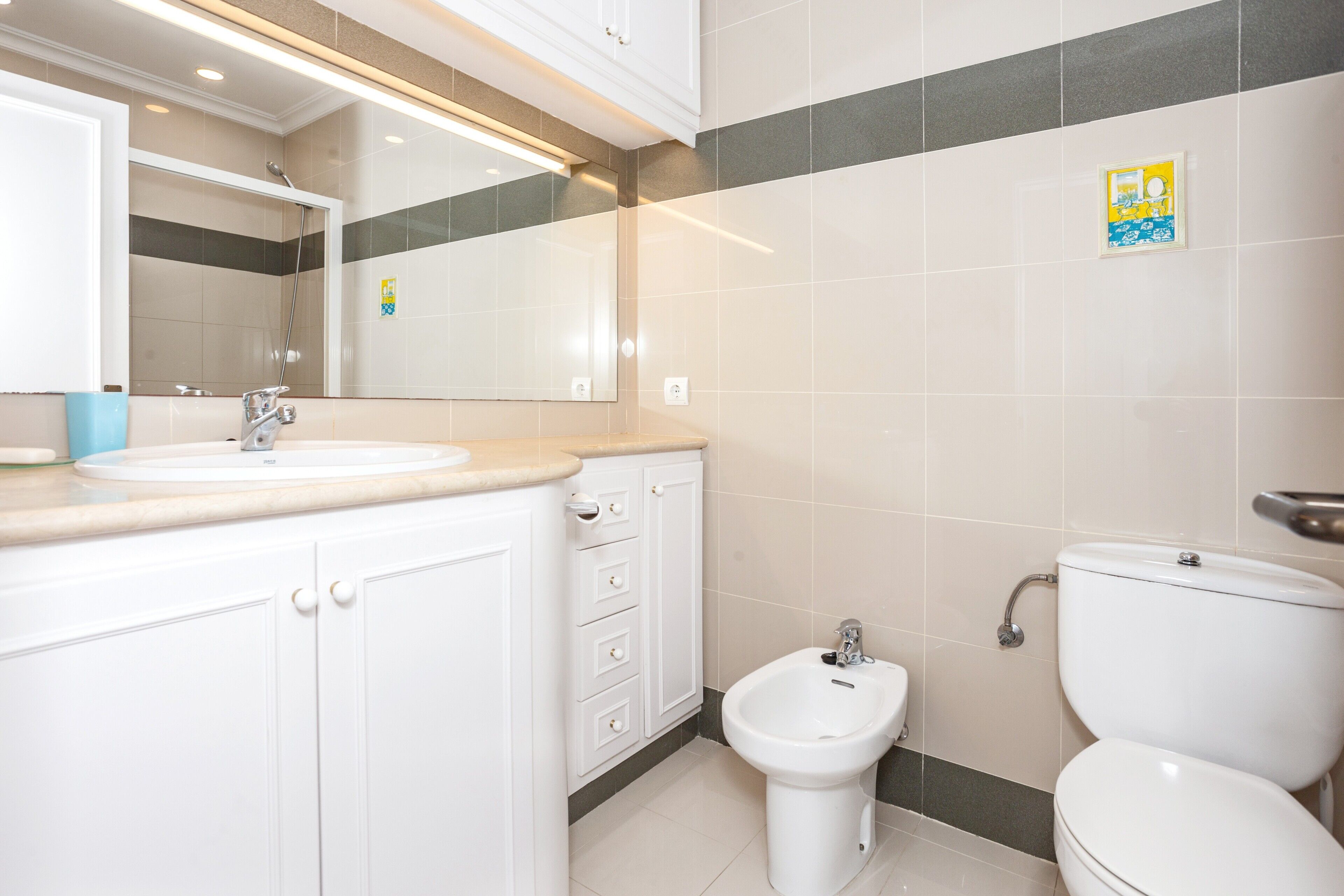 Une salle de bain équipée d’un lavabo, d’un miroir, d’un meuble de rangement, d’un bidet et de toilettes.