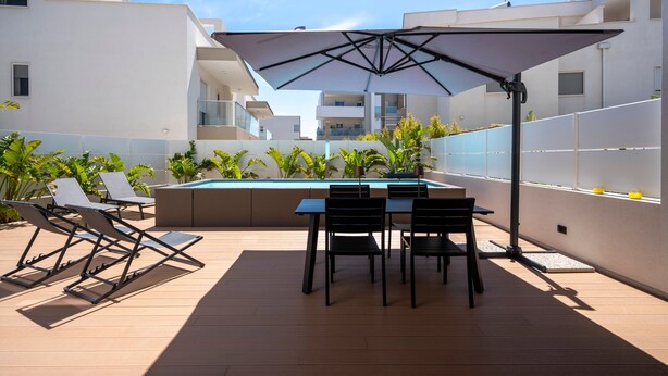 Une terrasse extérieure moderne avec une piscine, des chaises longues et une table avec des chaises.