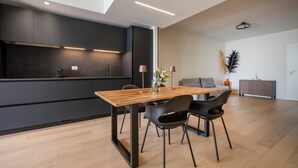 Une cuisine moderne avec des meubles de rangement sombres, une table à manger en bois et des chaises noires.
