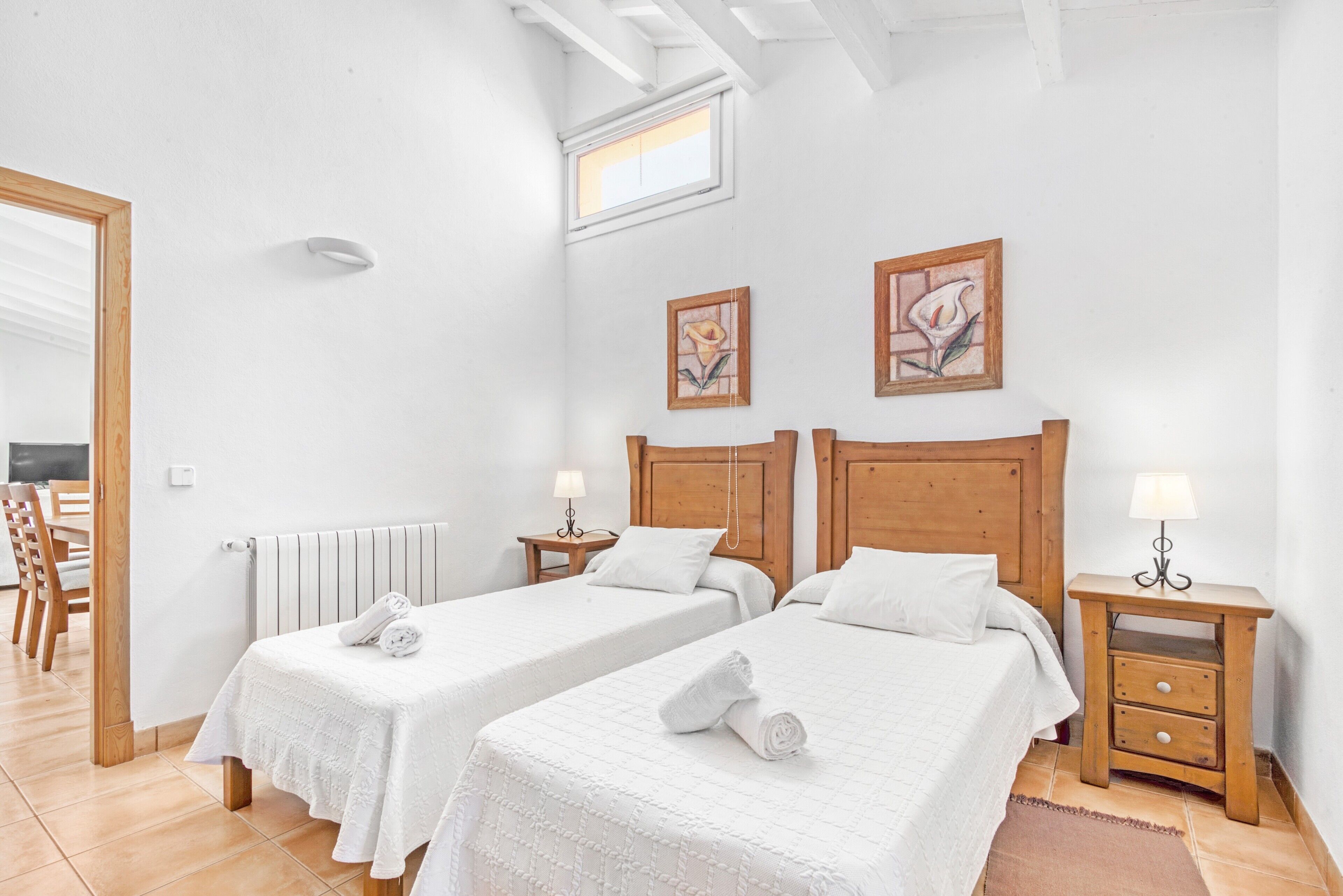 A room with two beds, wooden headboards, a window, and a radiator.