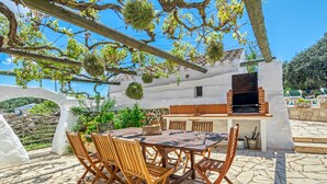 Un patio al aire libre con horno de ladrillo, sillas de madera y una mesa.