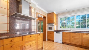 A kitchen with wooden cabinets, a stainless steel range hood, a built-in oven, and a dishwasher.