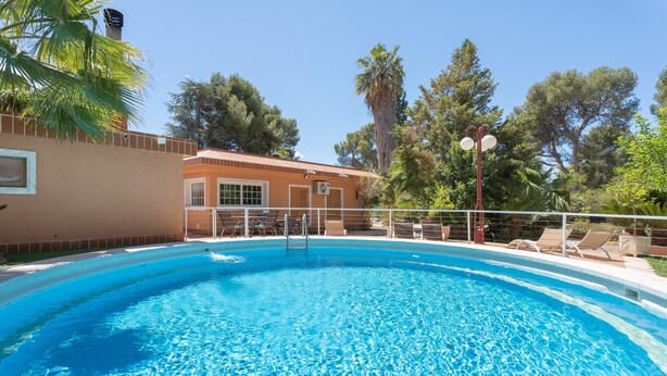 A swimming pool with lounge chairs and a building in the background.
