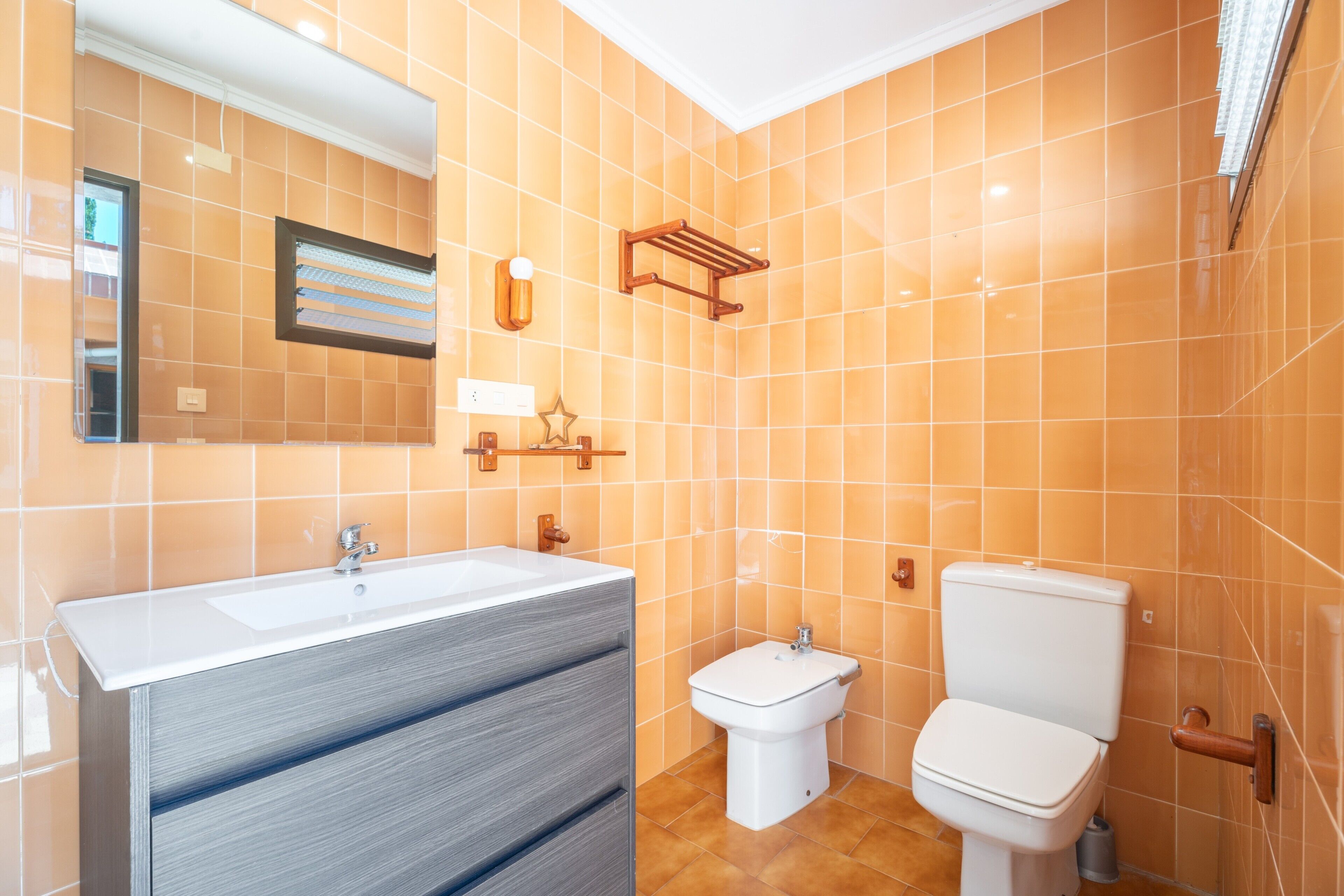 Een badkamer met een grote spiegel, een wastafel, een toilet en een bidet.
