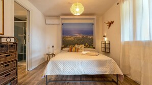 A bedroom with a bed, a view poster, a chandelier, and a wall-mounted lamp.