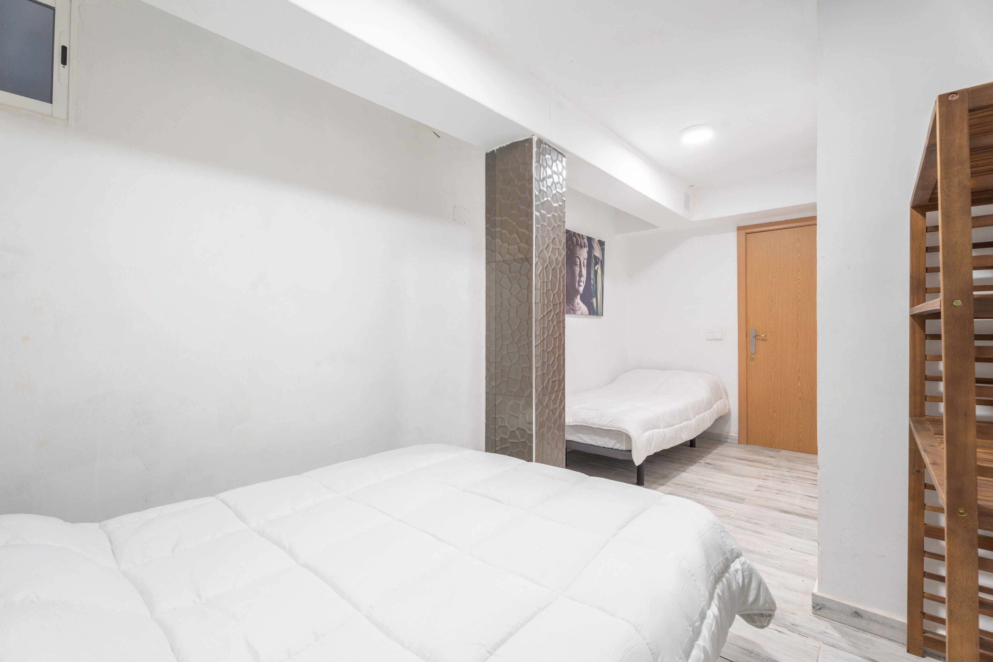 Une chambre à coucher avec un lit, une porte en bois et un escalier.