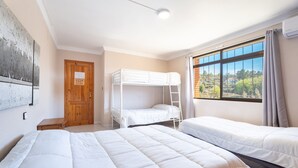 A room with bunk beds, a wooden door, a window with a view, and a ceiling light. - Chalet 'Castellana' with Mountain View, Wi-Fi and Air Conditioning (bicorp)