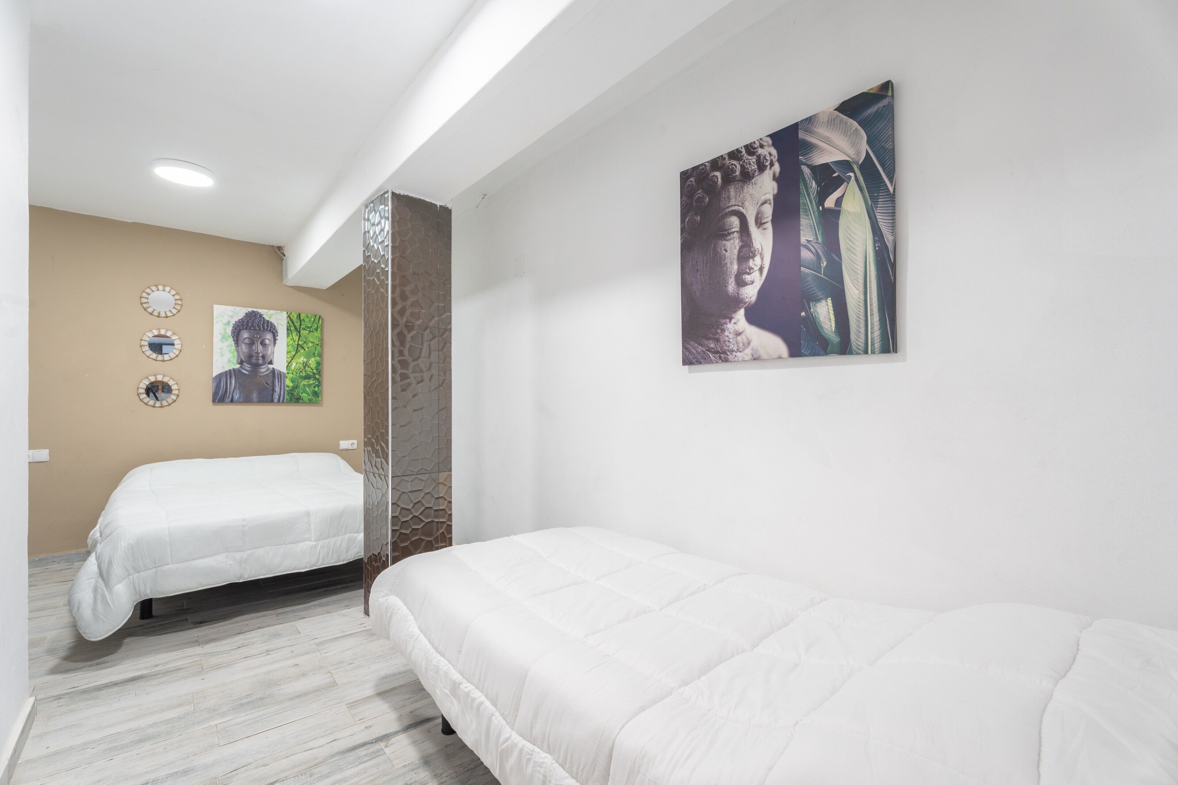 Een hotelkamer met twee bedden, een Boeddha-schilderij en een wandklok.
