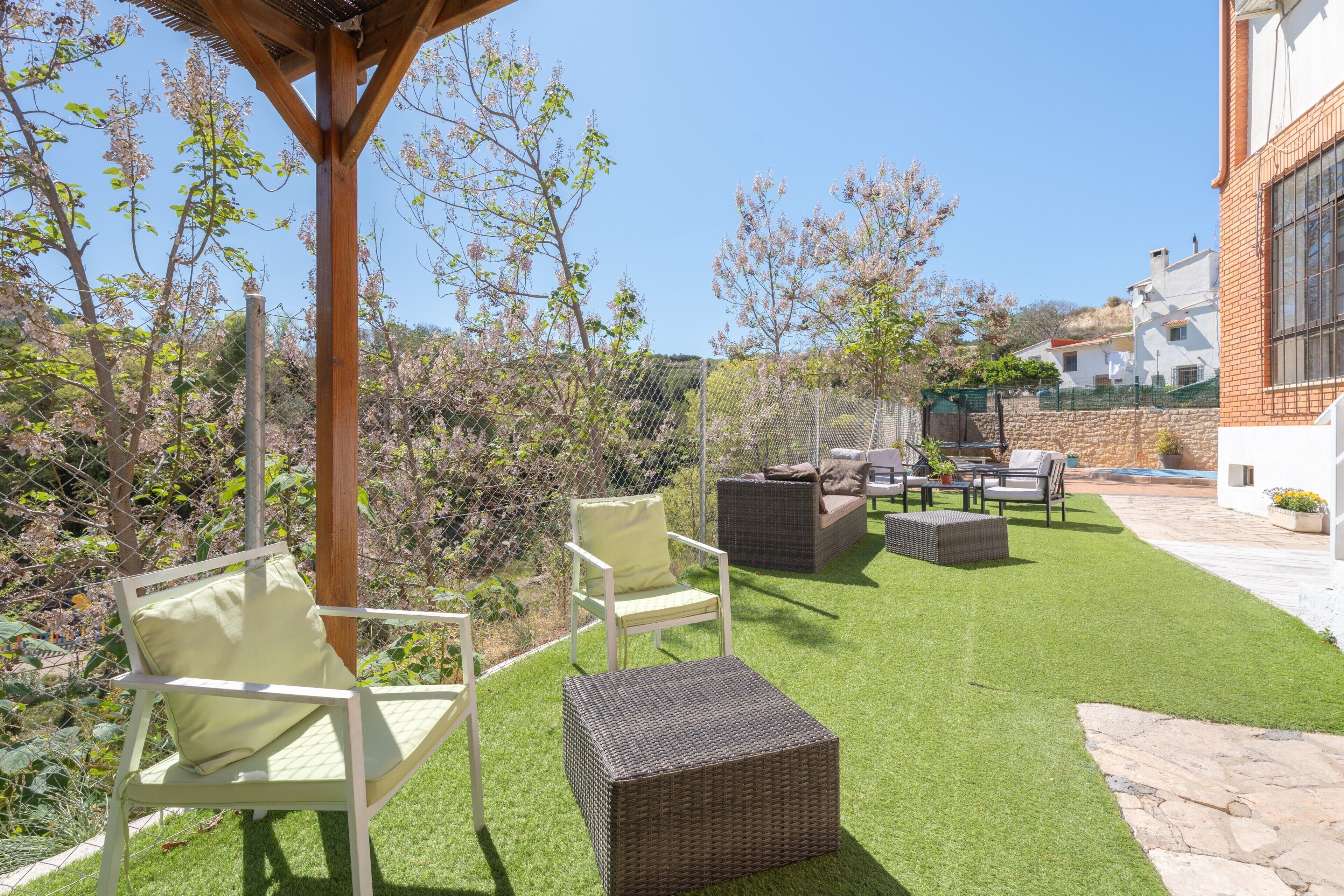 Une terrasse avec des meubles d’extérieur, une pergola et une vue sur une colline.