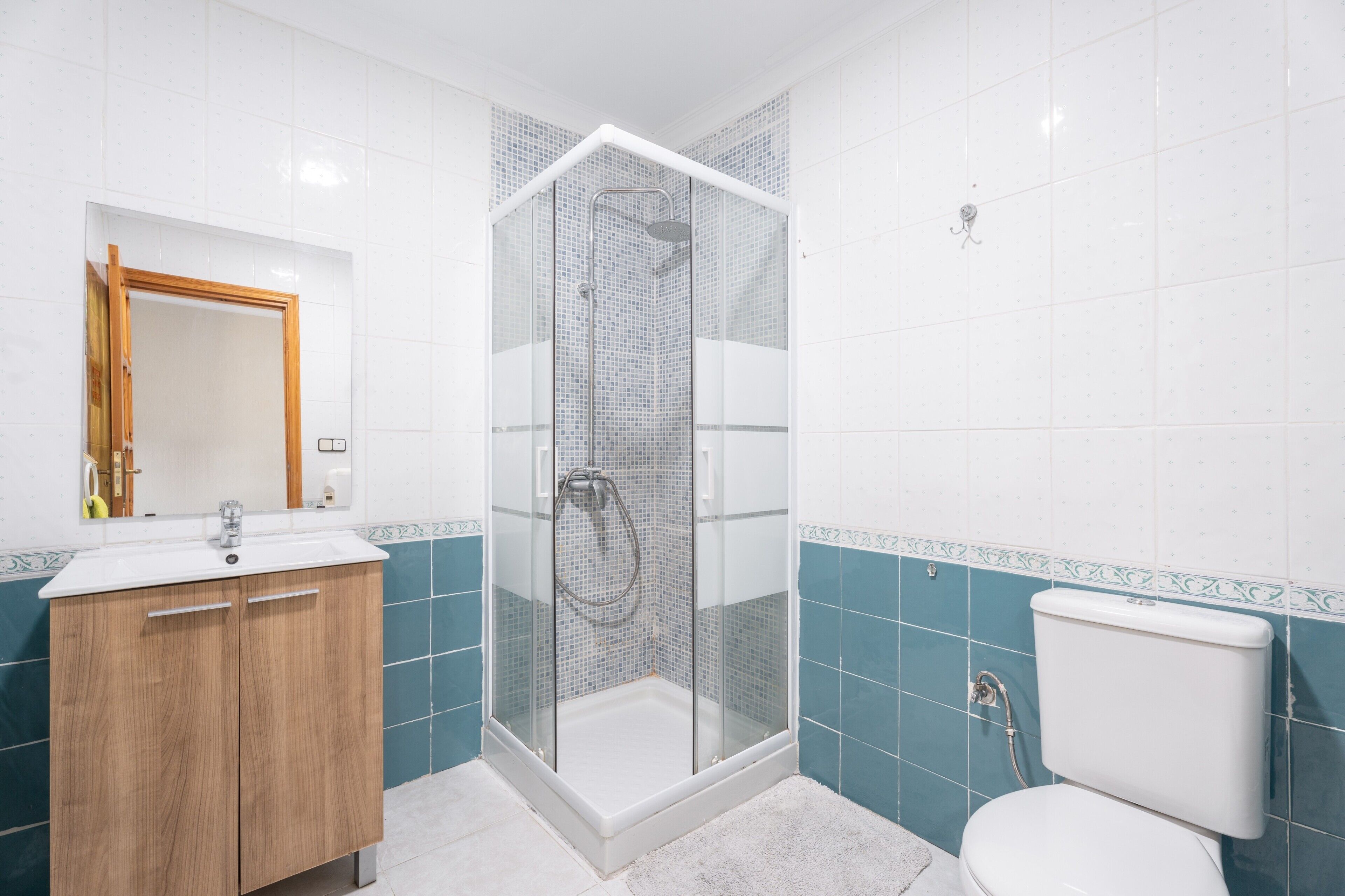 Un baño con ducha de vidrio, tocador de madera y un inodoro.