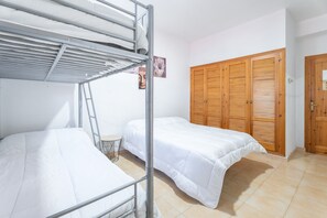 A room with bunk beds, a wooden wardrobe, and a small round table.