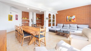 A spacious living area with a wooden dining table, sofas, and a brick accent wall. - Chalet 'Castellana' with Mountain View, Wi-Fi and Air Conditioning (bicorp)