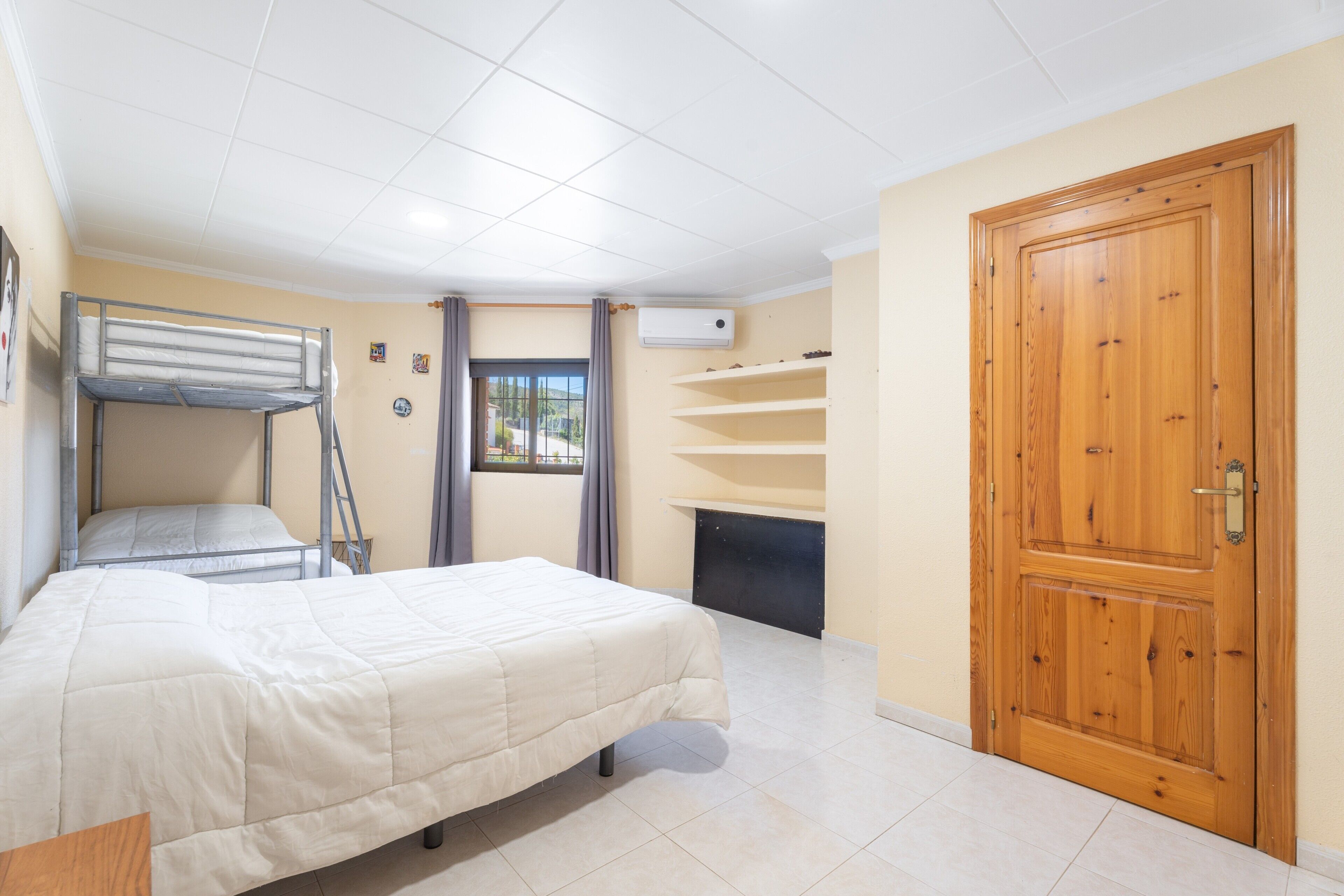 Ein Zimmer mit Etagenbetten, Kamin, Holztür und einem Fenster mit Vorhängen.