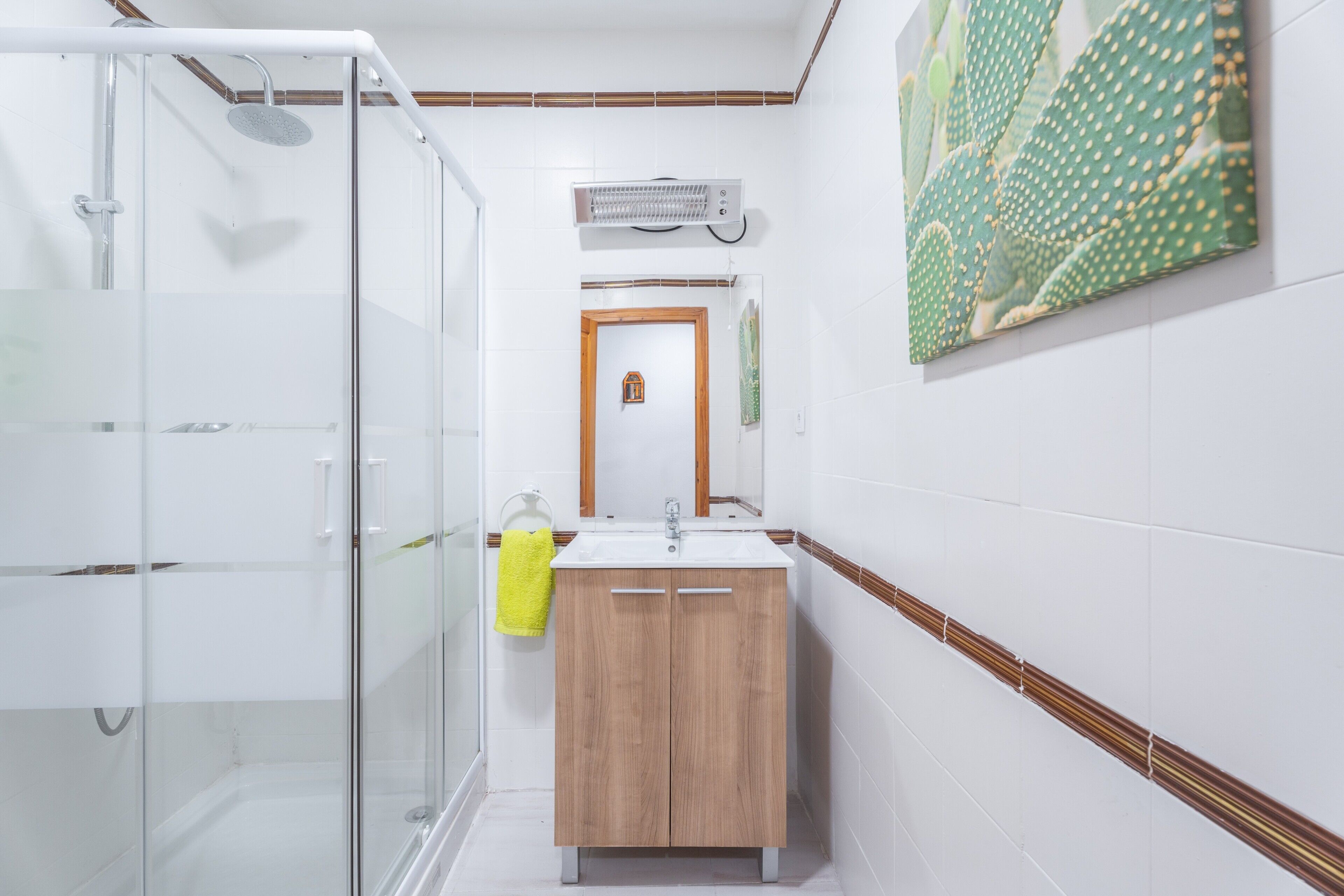 Un baño con cabina de ducha de vidrio, un armario de madera y un aire acondicionado de pared.