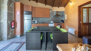 Une cuisine avec des meubles en bois, une cuisinière encastrée et un mur en pierre.