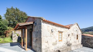 Un bâtiment en pierre avec un toit recouvert de tuiles, une porte et des fenêtres.
