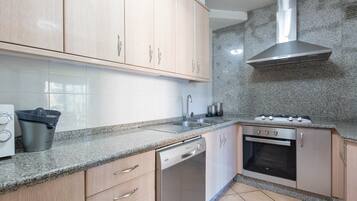A kitchen with wooden cabinets, a dishwasher, a stove, and a granite countertop.