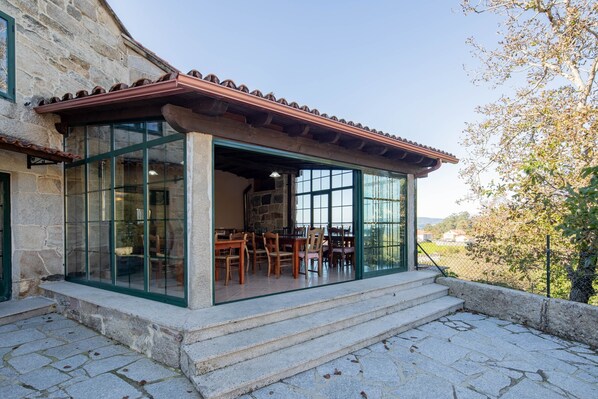 Edificio de piedra con un patio cubierto que incluye una mesa y sillas.
