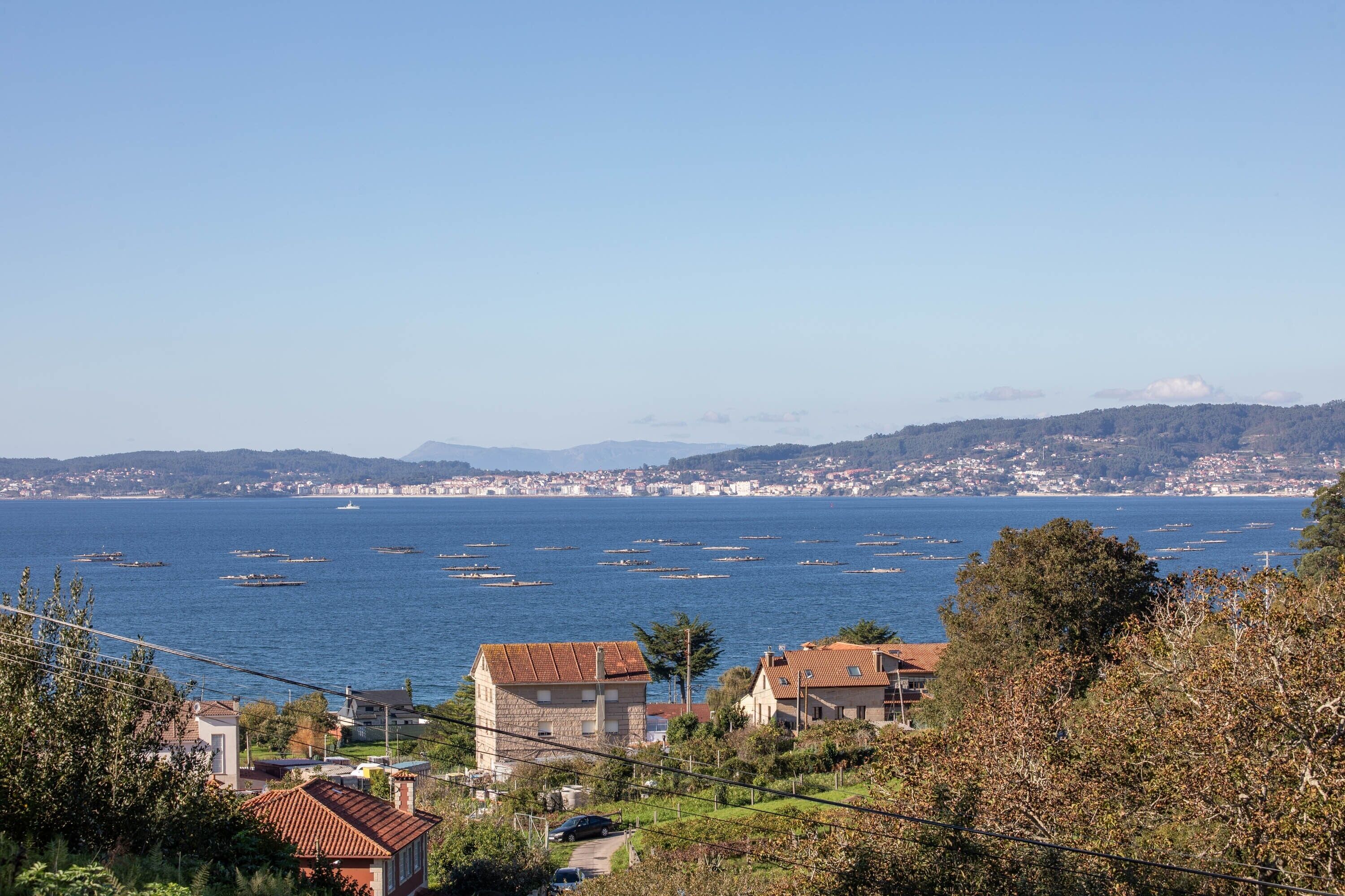 Uma vila costeira com casas, mar azul cristalino e barcos.