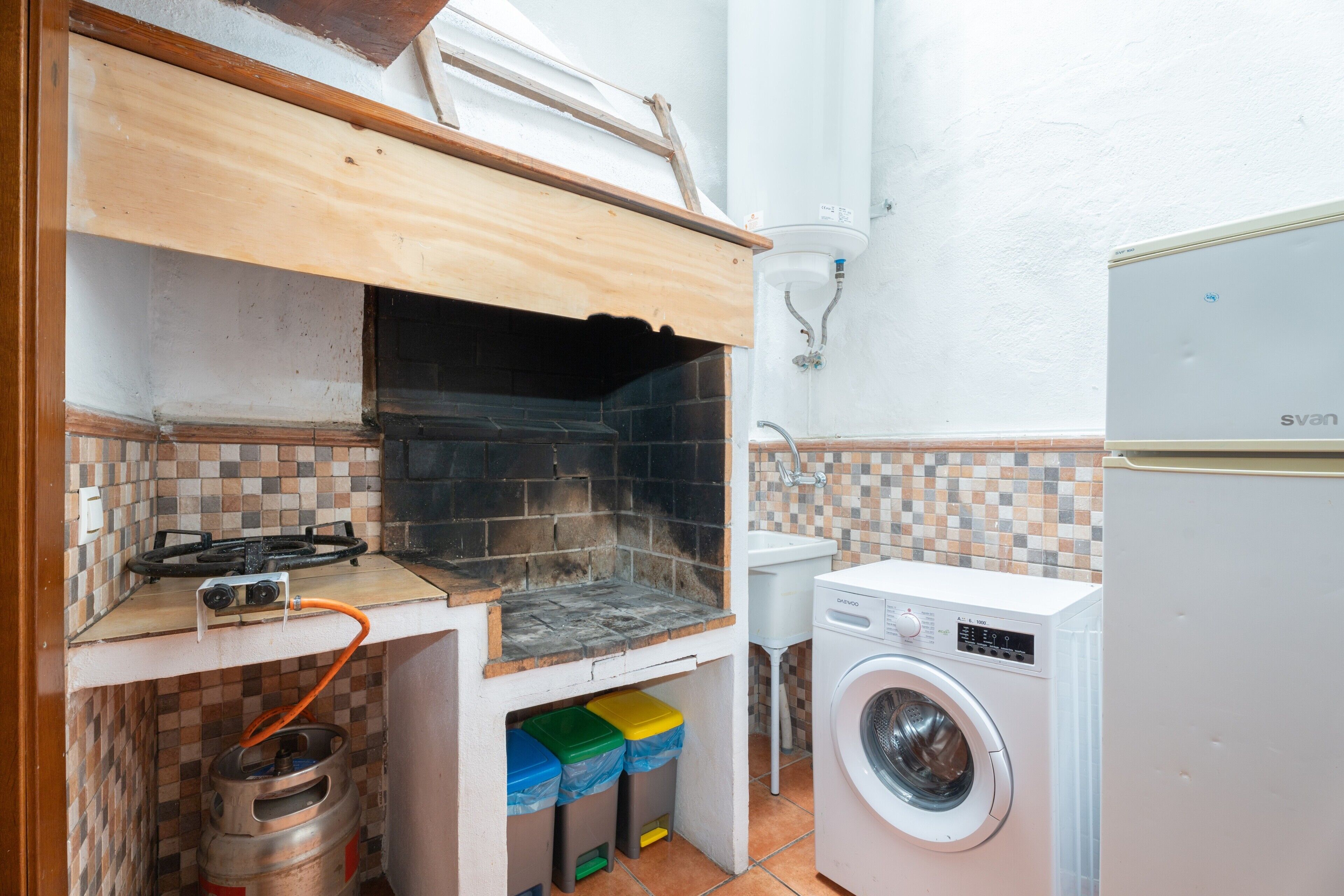 Una cocina compacta con estufa a gas, lavadora y salpicadero de azulejos.