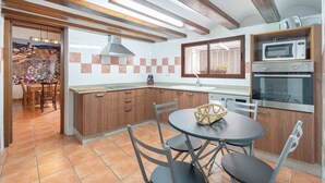 A modern kitchen with wooden cabinets, a central island, and built-in appliances.