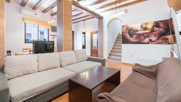 A living room with a sofa, a coffee table, a TV, and a staircase.