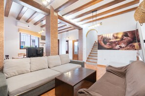 A living room with a sofa, a coffee table, a TV, and a staircase. - Apartment 'Cazuma' with Wi-Fi and Air Conditioning (Bicorp)