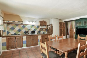 Une cuisine avec un mur recouvert de carreaux, des meubles en bois, un four à micro-ondes et une table à manger avec des chaises.