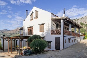 Un bâtiment à deux étages doté d’un balcon, d’une terrasse couverte et surplombant un paysage montagneux.