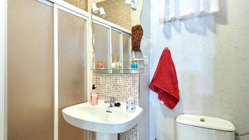 A bathroom with a white sink, a mirror, a red towel, and a toilet.