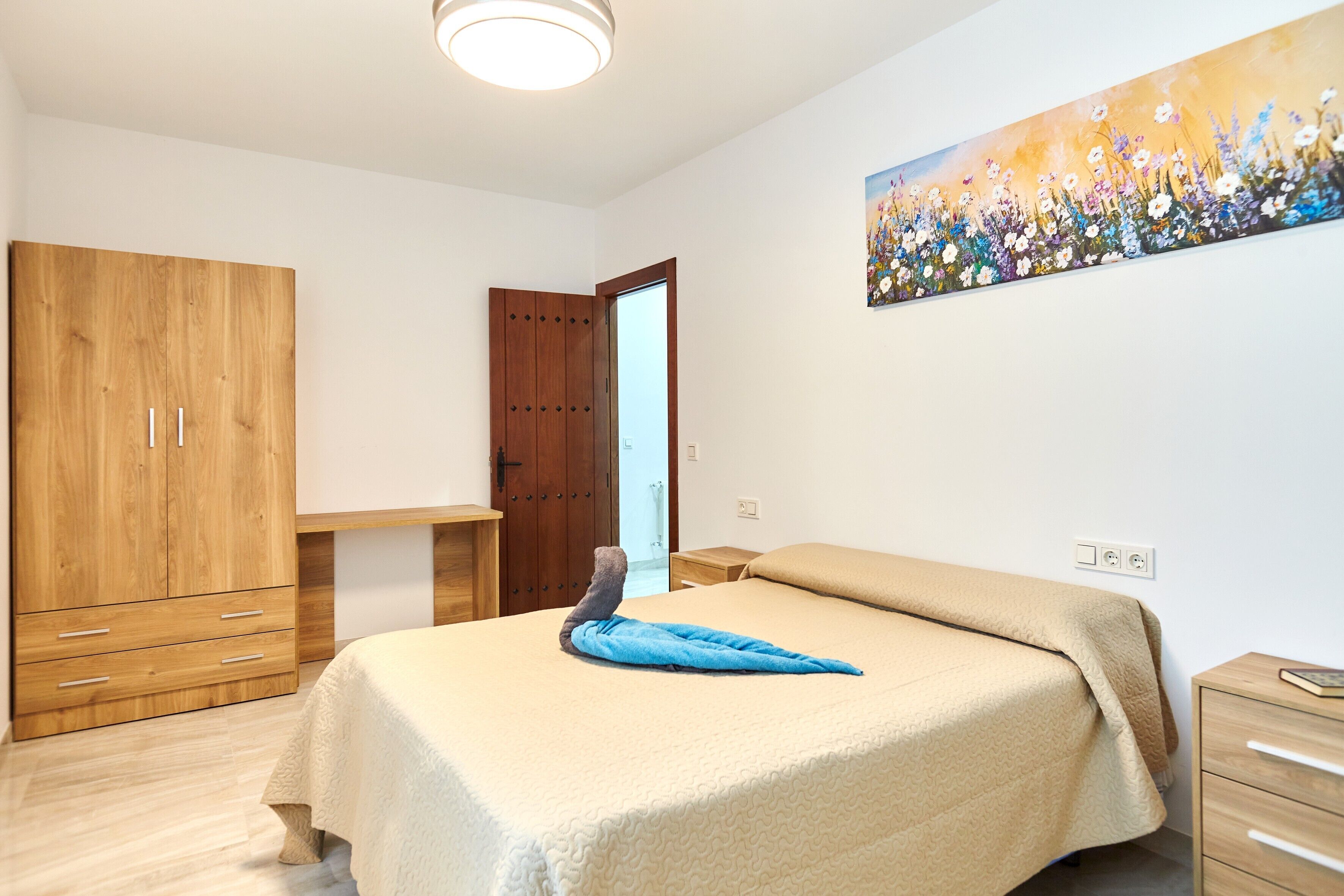 Ein Schlafzimmer mit einem Bett, einem Holzschrank und einem Bild an der Wand.