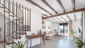 Ein modernes Interieur mit Treppe, einer Sofagarnitur, einem Couchtisch und Blick durch eine Glastür.