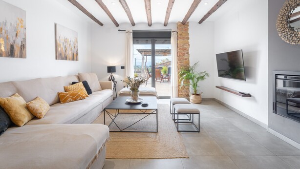 Ein modernes Wohnzimmer mit einer Couch, einem Couchtisch, einem Fernseher und einer Stein Säule.