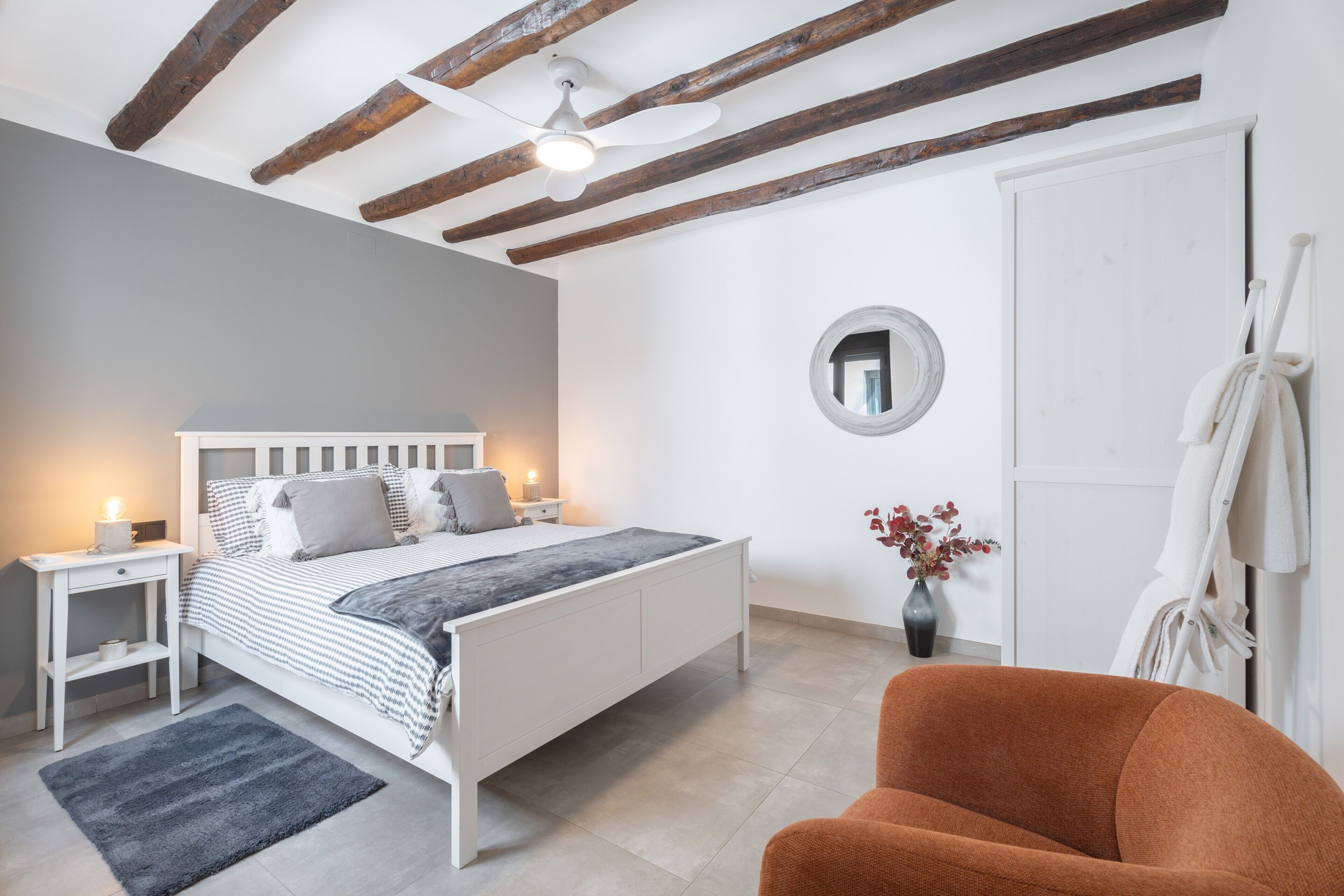 Una camera da letto con un letto, un comodino, una sedia e uno specchio a parete.