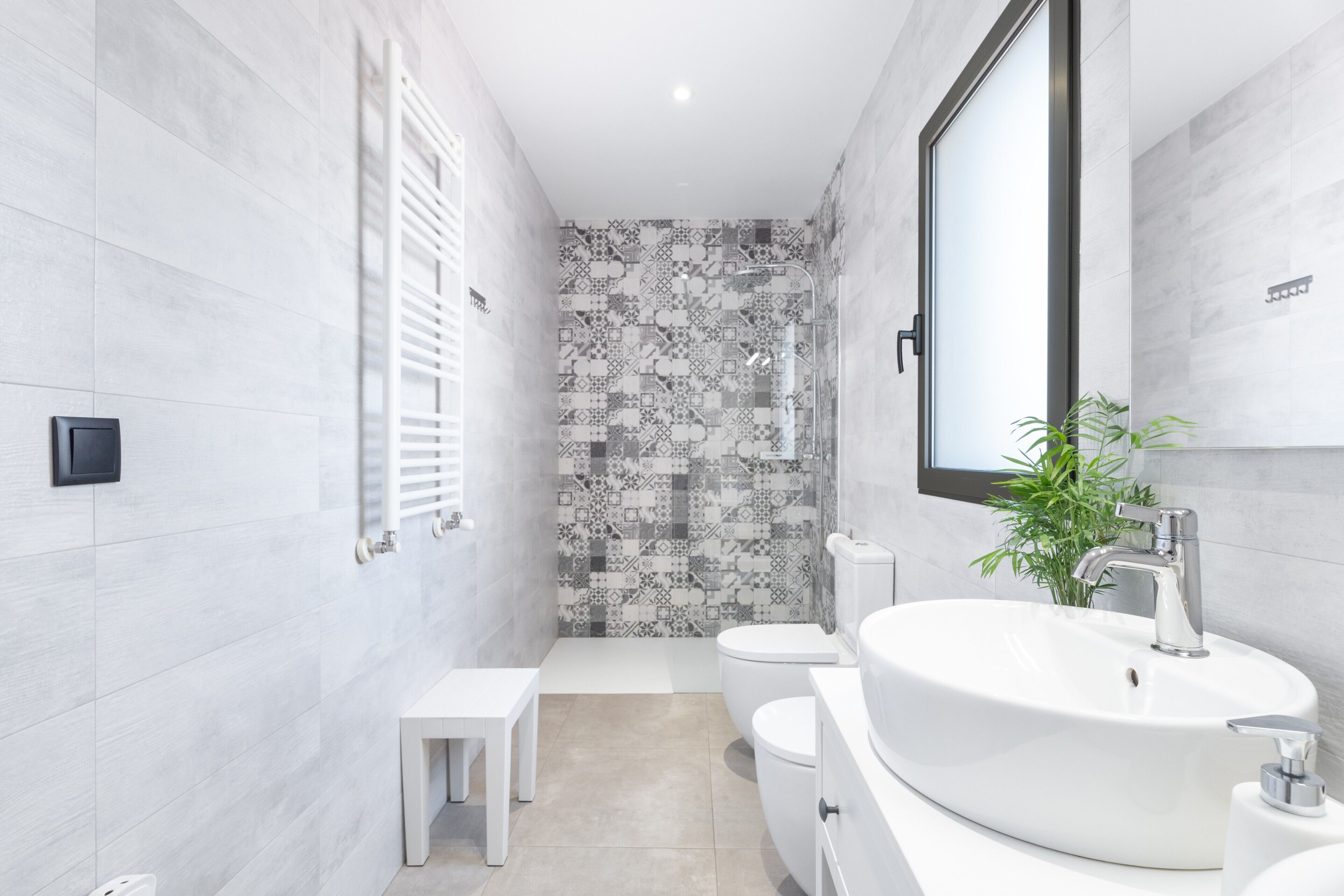 Une salle de bain moderne avec un lavabo, des toilettes et une zone de douche, le tout de couleur blanche.