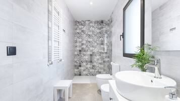 Une salle de bain moderne avec un lavabo, des toilettes et une zone de douche, le tout de couleur blanche.