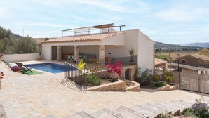 Eine moderne Villa mit Swimmingpool, Sitzgelegenheiten im Freien und Blick auf die Landschaft.