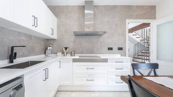 Una cocina moderna con armarios blancos, una campana extractora de acero inoxidable y un horno empotrado.