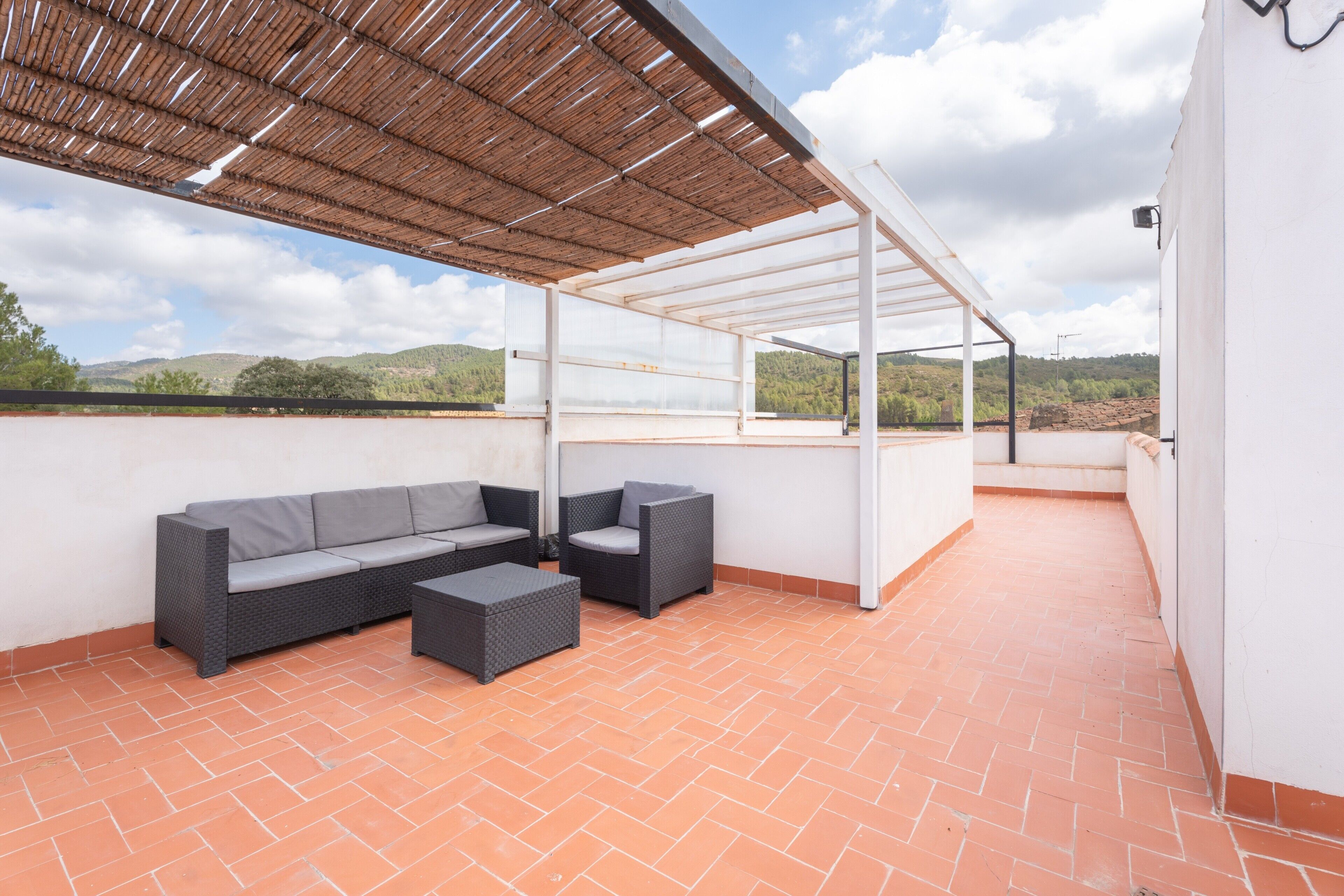 An outdoor patio with a sofa, chairs, and a table.