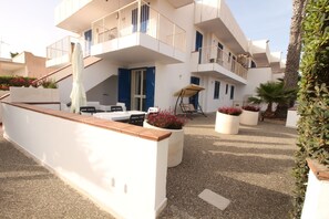 A modern building with multiple balconies, outdoor seating, and potted plants. - Residence Mare Azzurro (Ugento)
