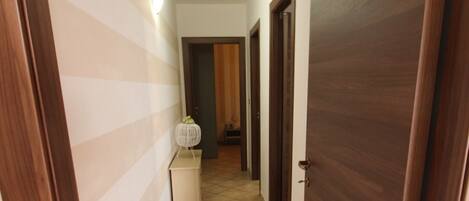 Un pasillo con paredes a rayas, suelo de baldosas y puertas de madera.