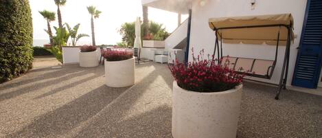 A rooftop terrace with potted plants, outdoor seating, and a swing chair.
