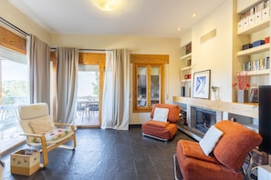 A living room with a fireplace, a bookshelf, and a dining area with a table and chairs. - Apartment 'Casa Rural Cantueso 1' with Mountain View, Private Terrace and Wi-Fi (La Matilla)