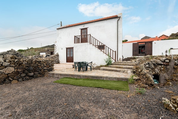 A white building with a red roof, a staircase, and a small outdoor seating area. - Holiday Home 'Casa Rural La Era' with Sea View, Private Terrace and Wi-Fi (Valverde)