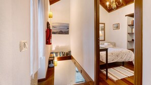 Une chambre à coucher comprenant un lit, une table de chevet, une commode, une fenêtre, un lustre et une bibliothèque.