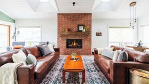 A living room with a brick fireplace, leather sofas, and a patterned rug. - DT Flag | Epic Game Room | AC | Hot tub | Fire Pit (Flagstaff)