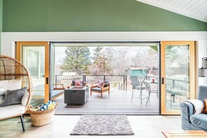 Ein modernes Wohnzimmer mit einem großen Schiebeglasfenster, das auf eine Terrasse im Freien führt.