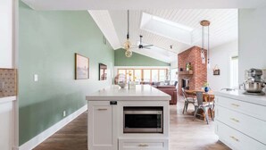 A kitchen with a built-in microwave, a dining area with a wooden table and chairs, and a brick fireplace. - DT Flag | Epic Game Room | AC | Hot tub | Fire Pit (Flagstaff)